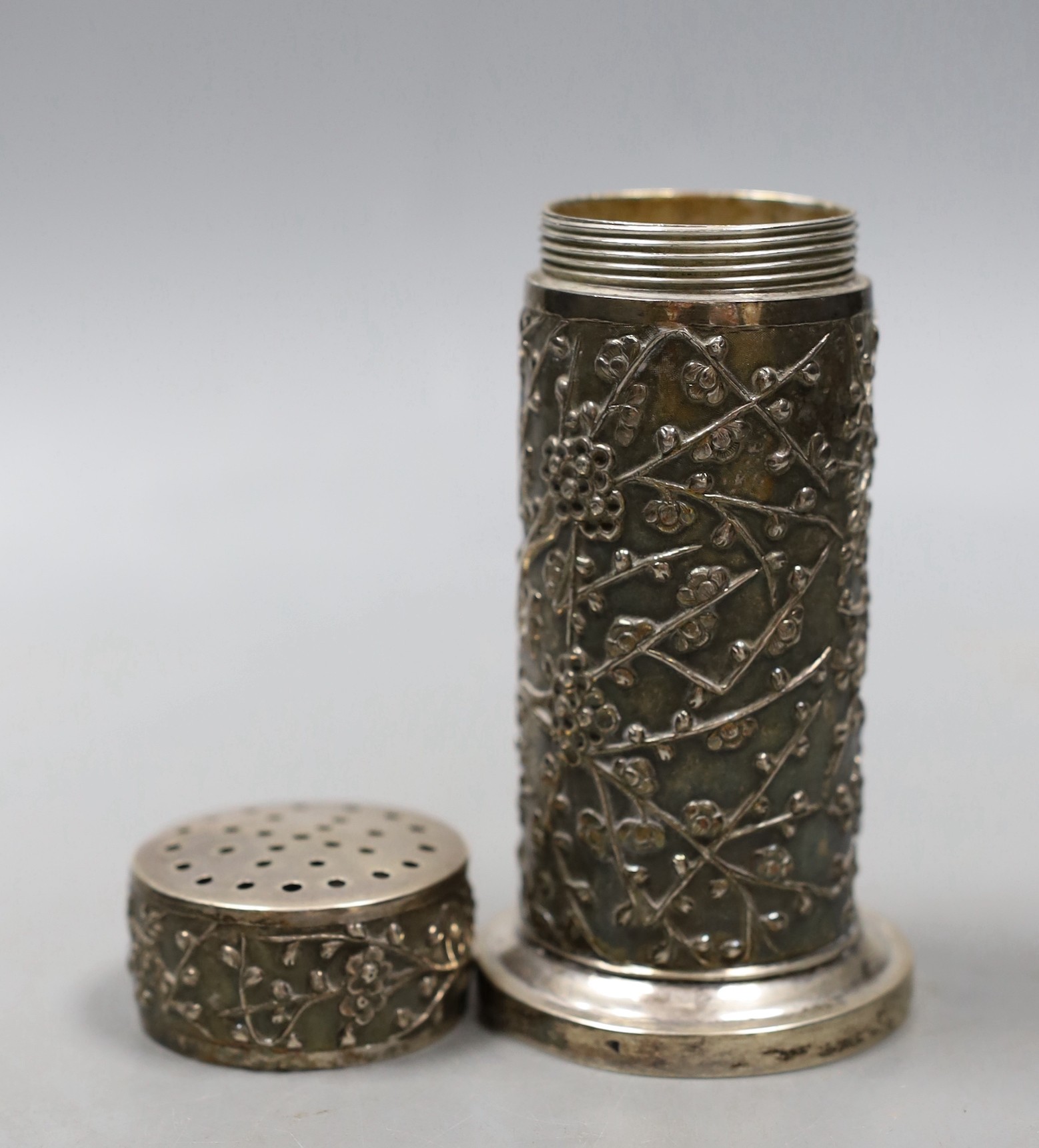 A late 19th/early 20th century Chinese Export white metal cylindrical sugar caster by Wang Hing, Hong Kong, decorated with prunus, 12.1cm, 170 grams.